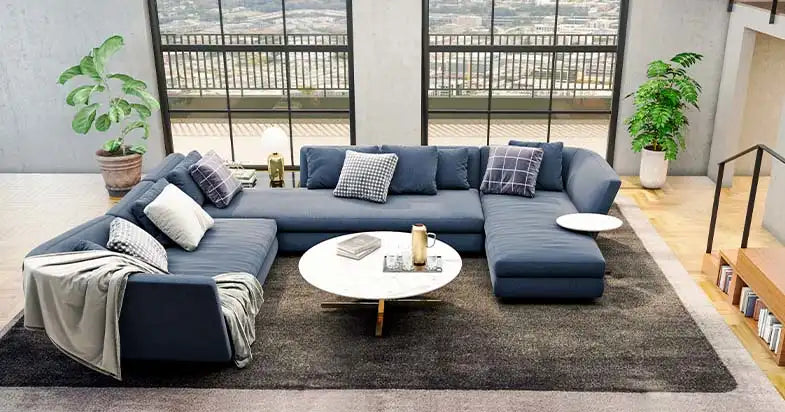 A large navy blue modular sectional lounge suite in a modern living room with large windows and a marble coffee table.