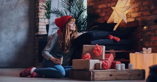 Woman in a red beanie relaxing next to holiday gift boxes during a Boxing Day sale with major price drops