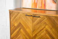 Walnut buffet with three drawers and two doors, displayed in a stylish storage space.